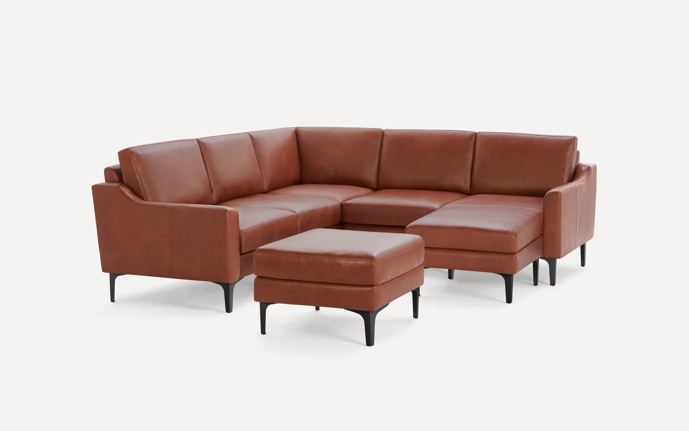Brown leather L-shaped sectional sofa with black legs, featuring a matching ottoman on a white background.
