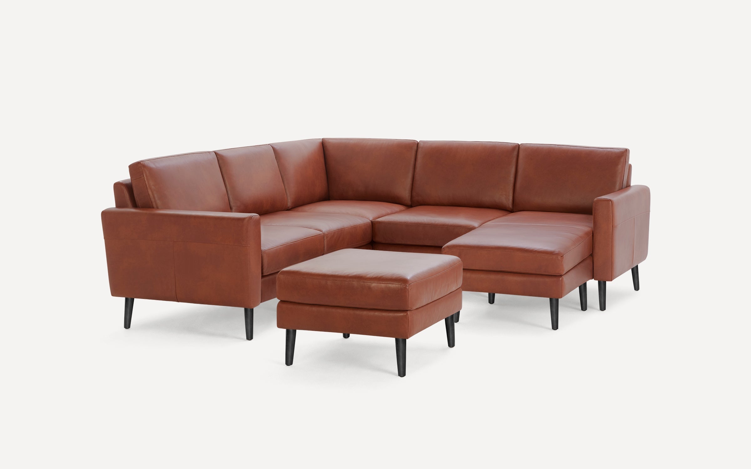 Brown leather sectional sofa with black legs and matching ottoman, featuring clean lines and modern design.