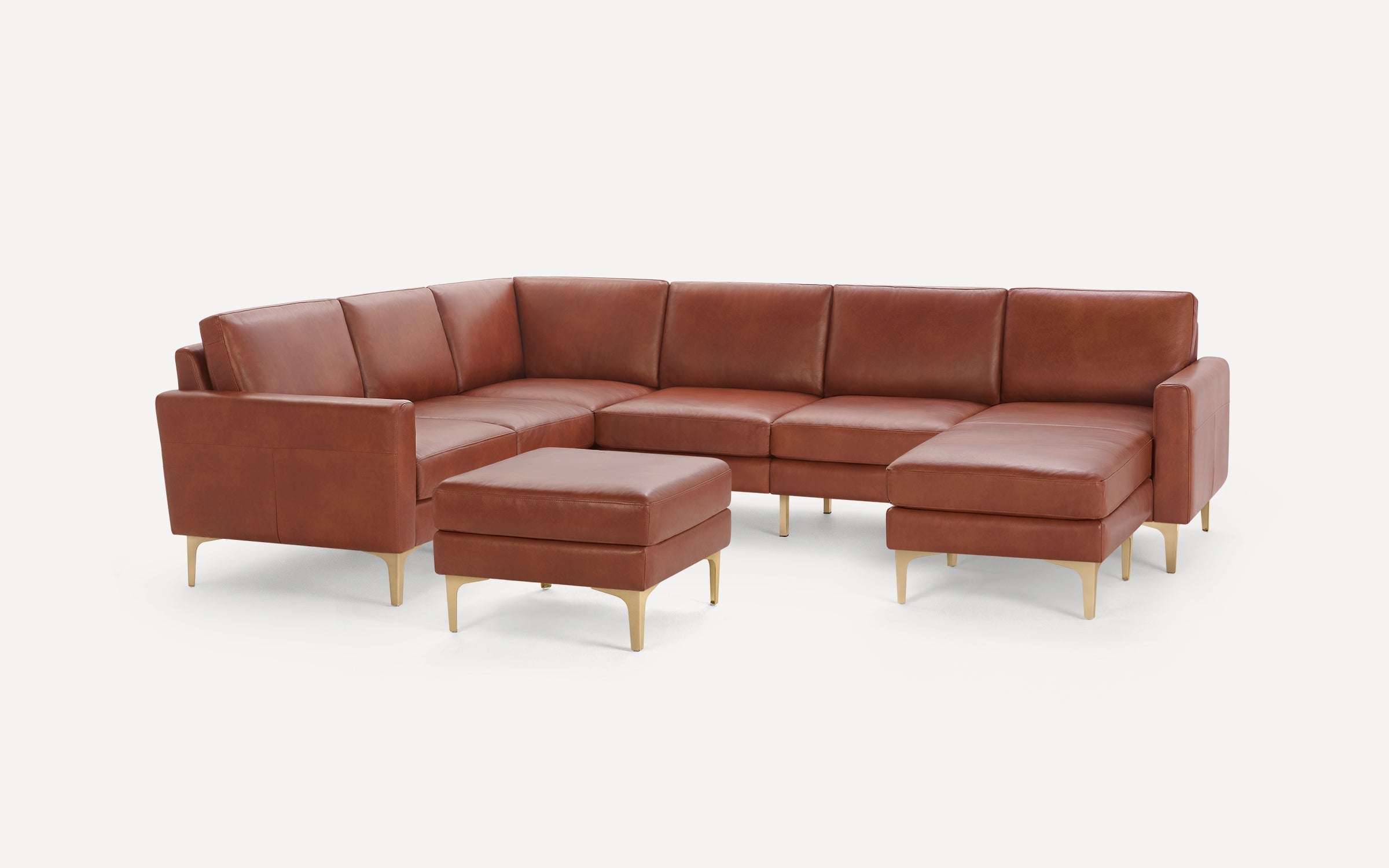 Brown leather sectional sofa with gold metal legs and matching ottoman, set against a plain white background.