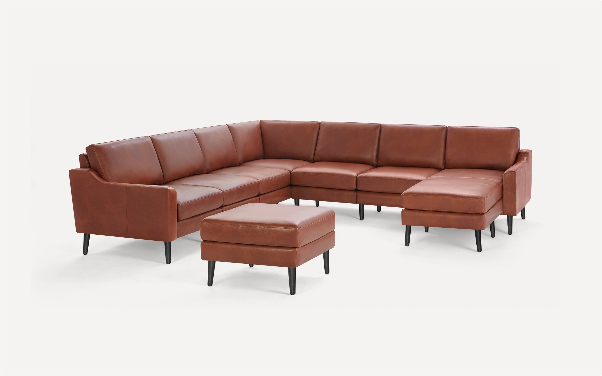 Brown leather sectional sofa with matching ottoman, black tapered legs, modern design, and clean lines.