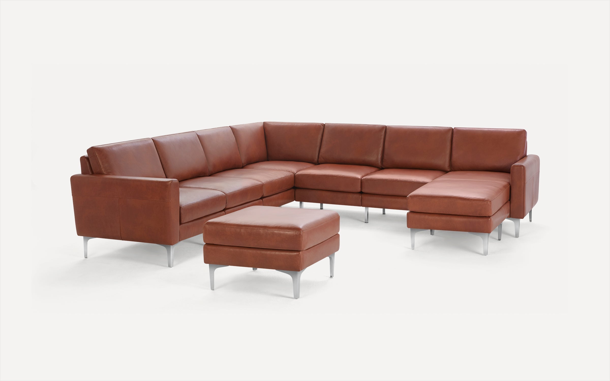 Modern brown leather sectional sofa with metal legs and matching ottoman on white background.