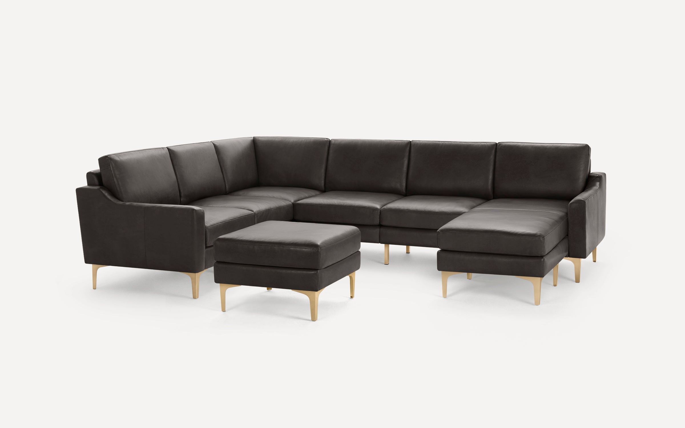 Dark grey sectional leather sofa with clean lines, gold metal legs, and a matching ottoman on a white background.
