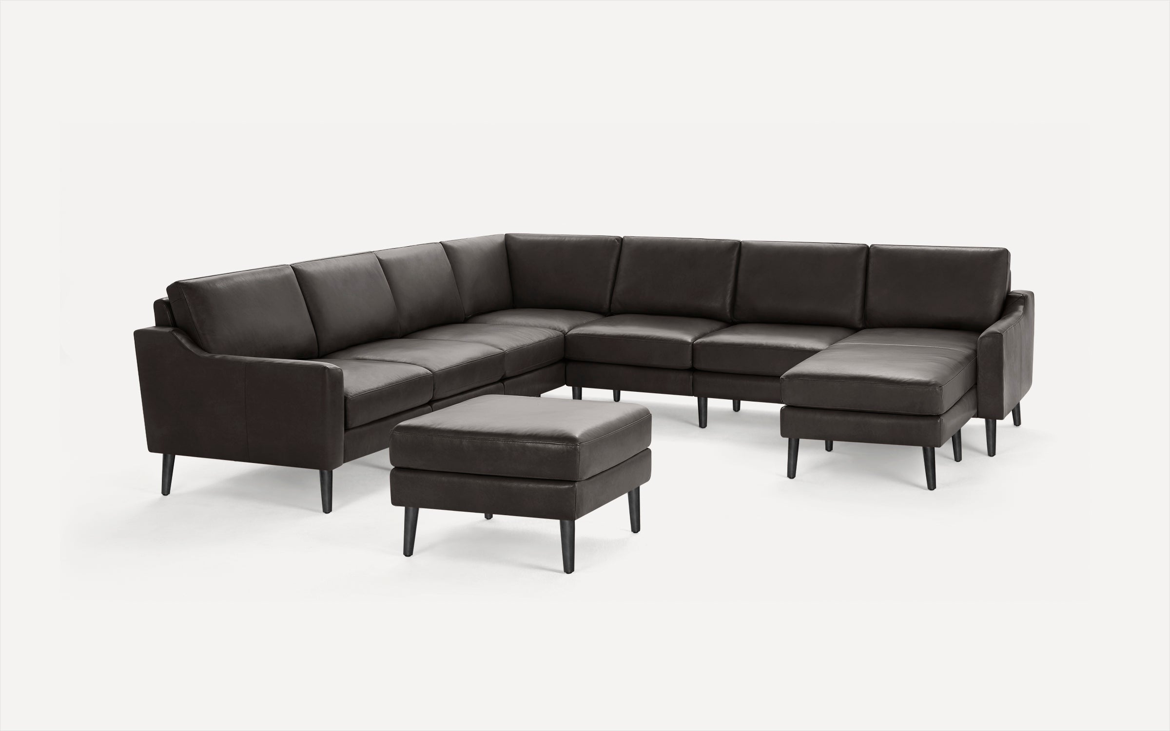 Dark brown leather sectional sofa with a matching ottoman, featuring sleek wooden legs and modern design.