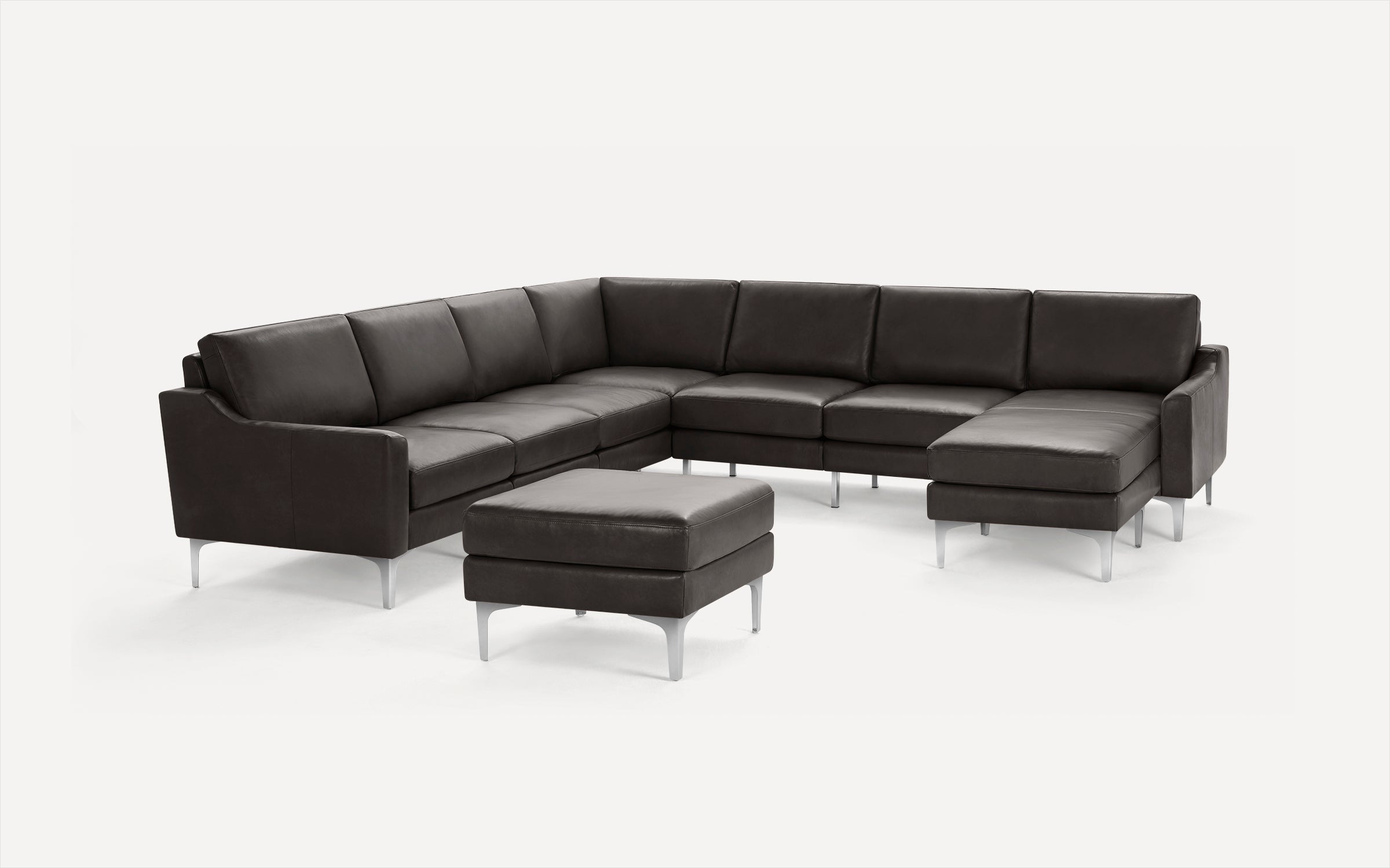 Dark brown leather sectional sofa with an ottoman, featuring sleek metal legs and modern design.