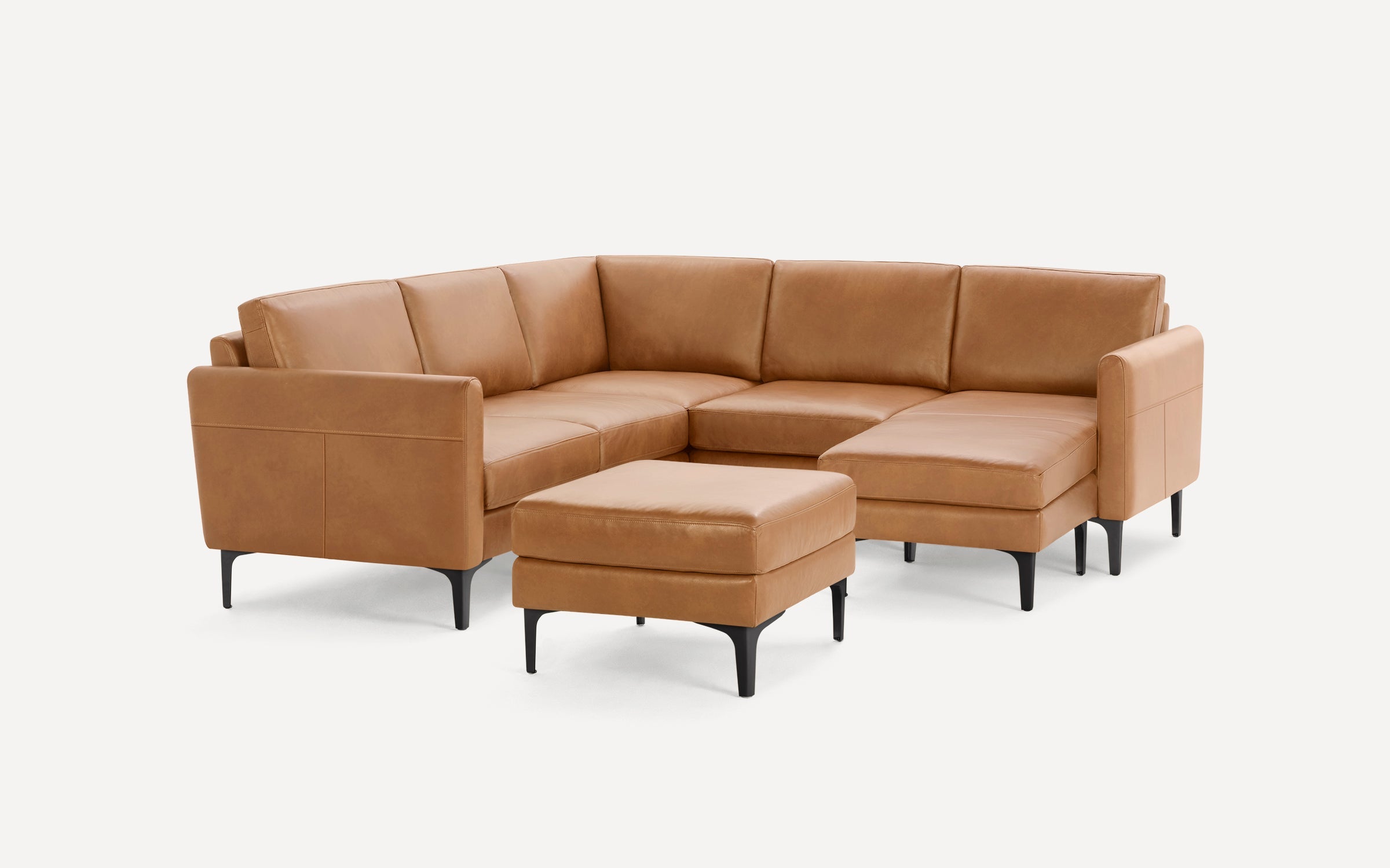 Modern tan leather sectional sofa with black metal legs, including a matching cushioned ottoman.