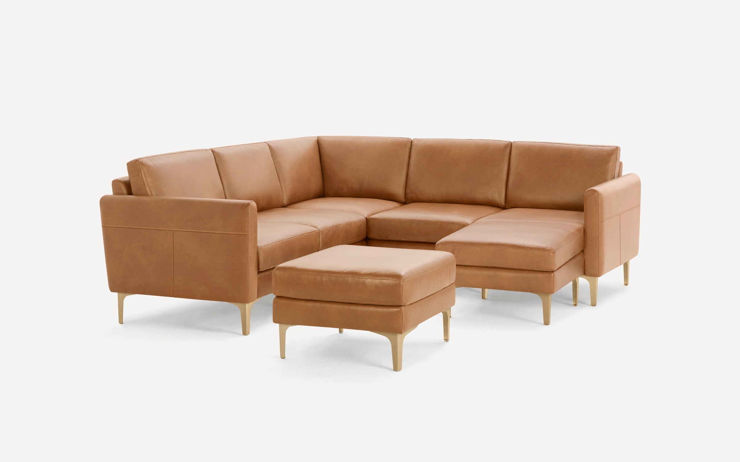 Modern tan leather sectional sofa with clean lines, gold-toned legs, and a matching ottoman on a white background.