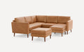 Modern tan leather L-shaped sectional sofa with wooden legs and matching ottoman, set against a white background.