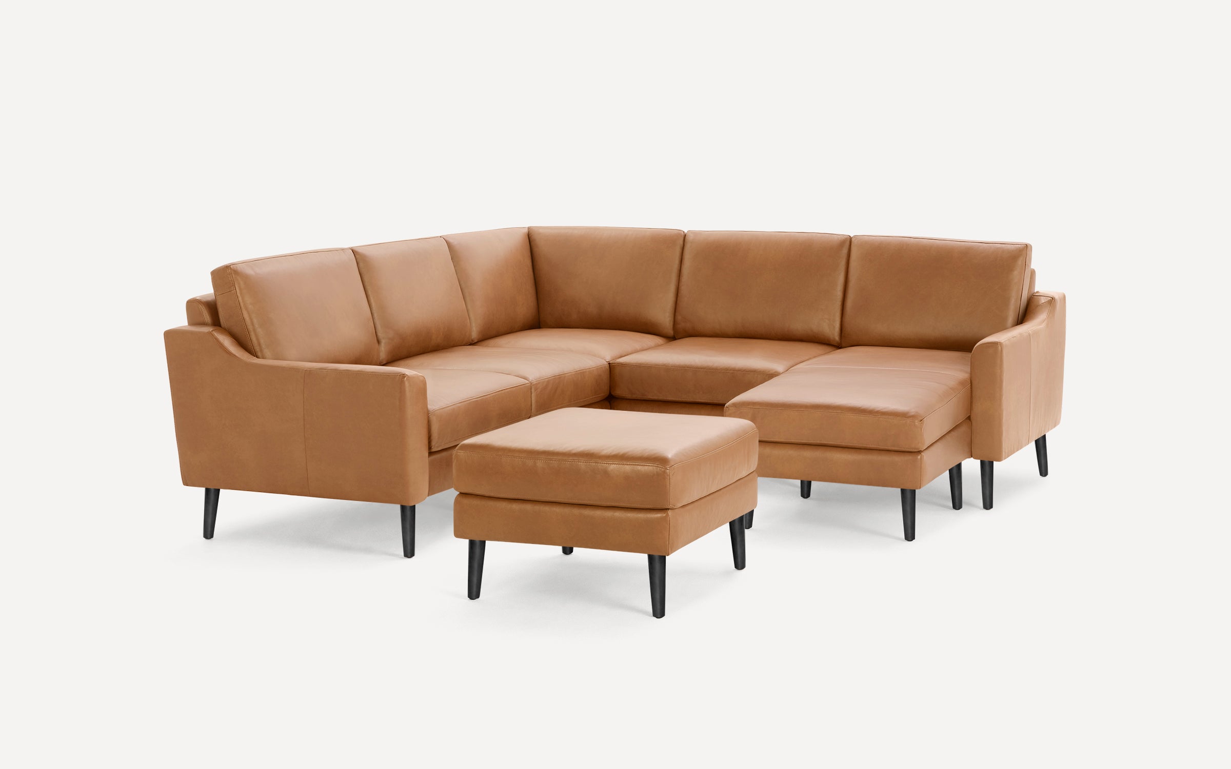 Tan leather L-shaped sectional sofa with clean lines, padded cushions, and black tapered legs, accompanied by a matching ottoman.