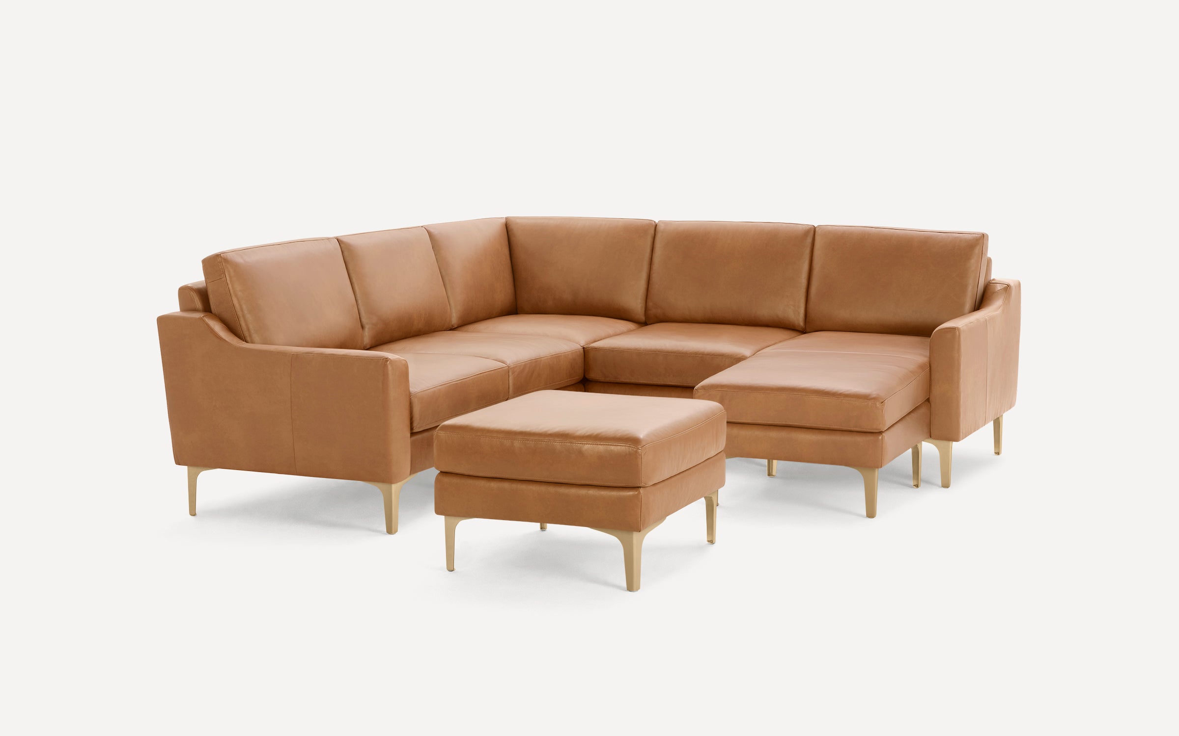 Modern tan leather sectional sofa with matching ottoman, featuring sleek gold legs and clean lines on a white background.