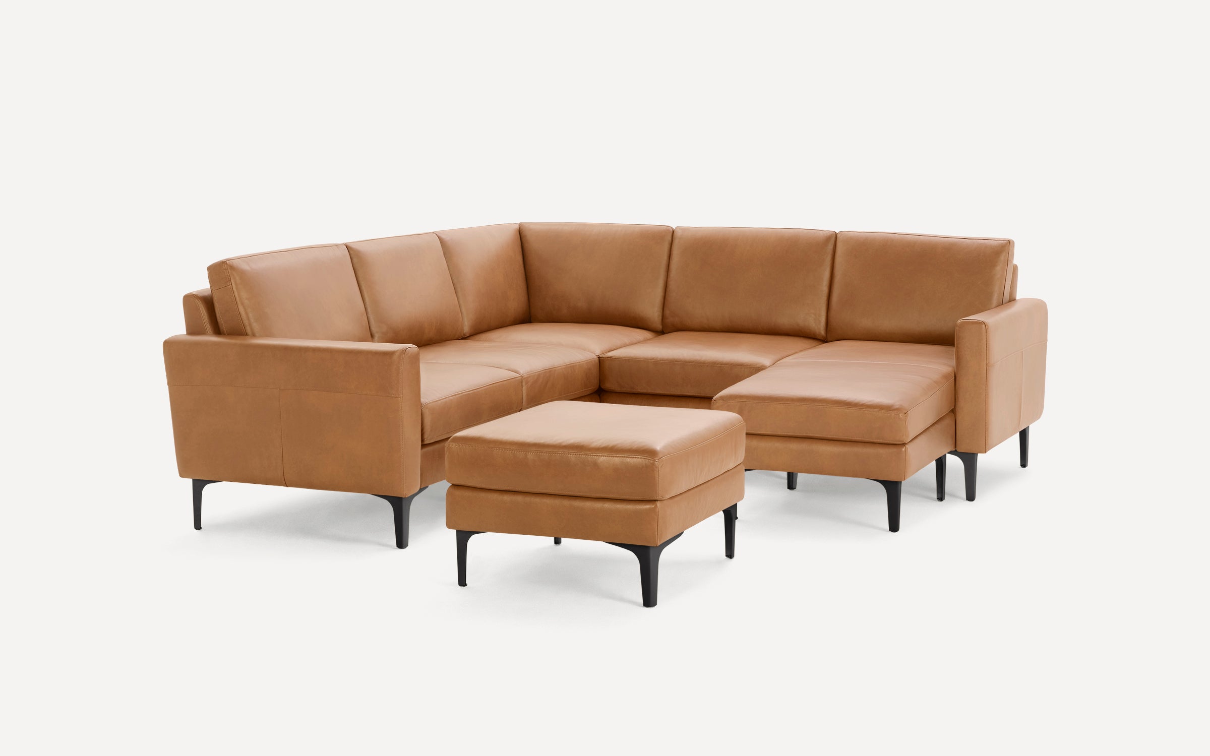 Modern tan leather sectional sofa with matching ottoman, black legs, and clean lines, set against a white background.
