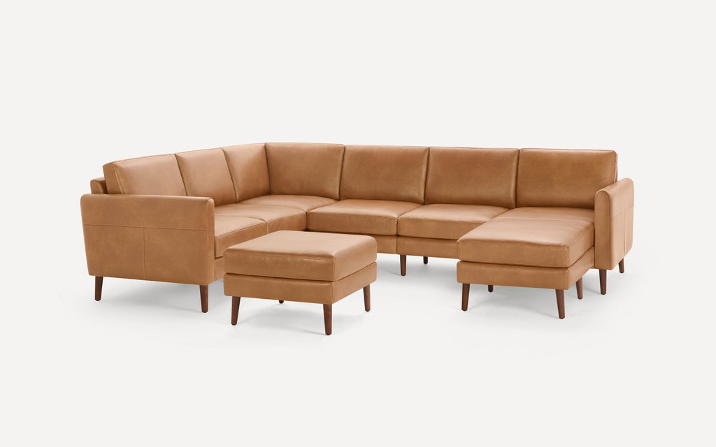 Modern L-shaped sectional sofa set in tan leather with matching ottoman, featuring sleek wooden legs and clean lines.
