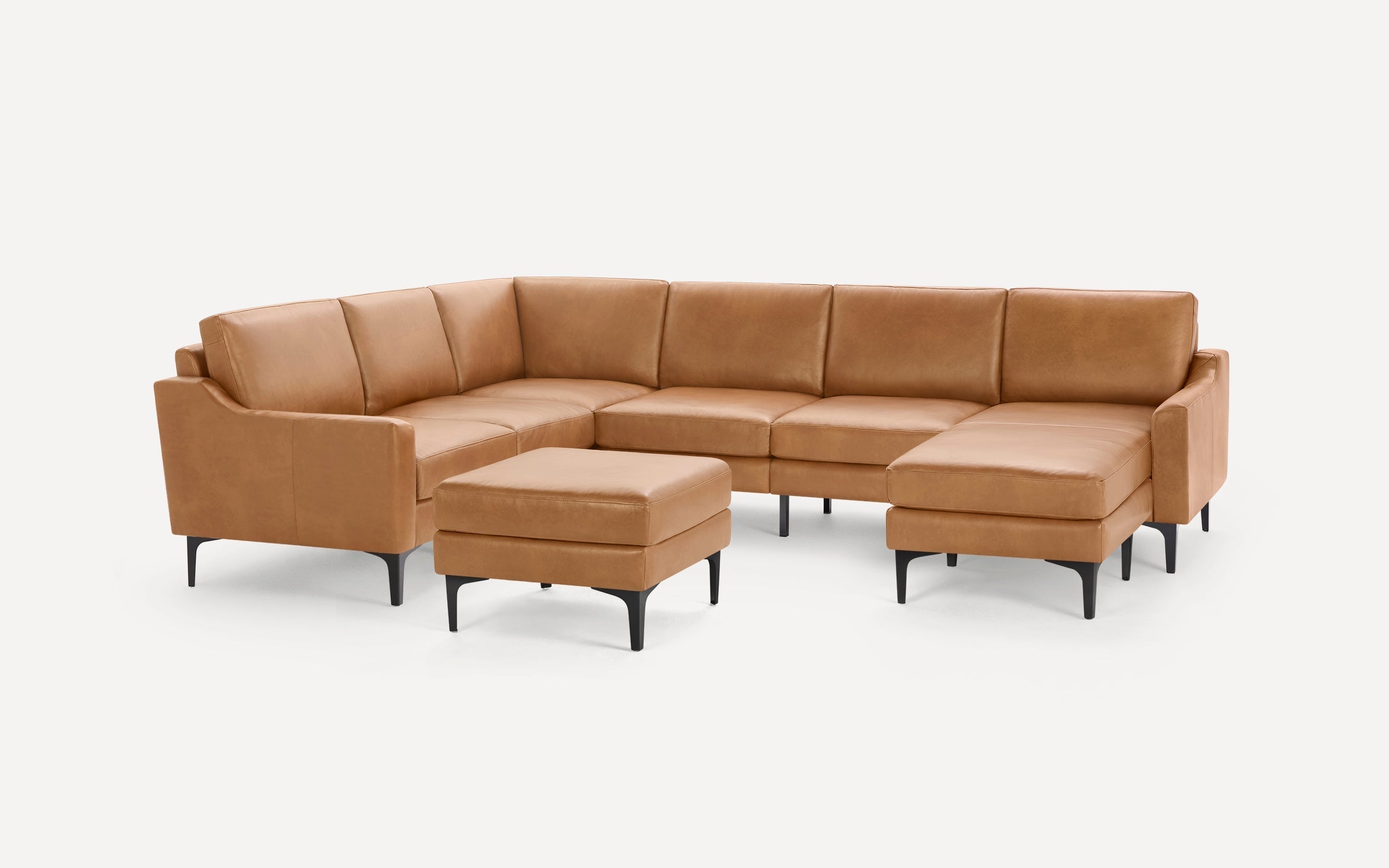 Modern L-shaped tan leather sectional sofa with black metal legs and matching ottoman on white background.