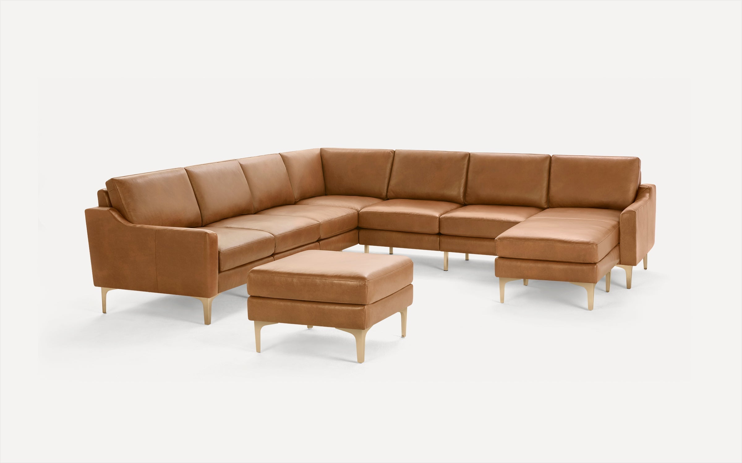 Modern tan leather L-shaped sectional sofa with matching ottoman, featuring sleek wooden legs and clean lines.