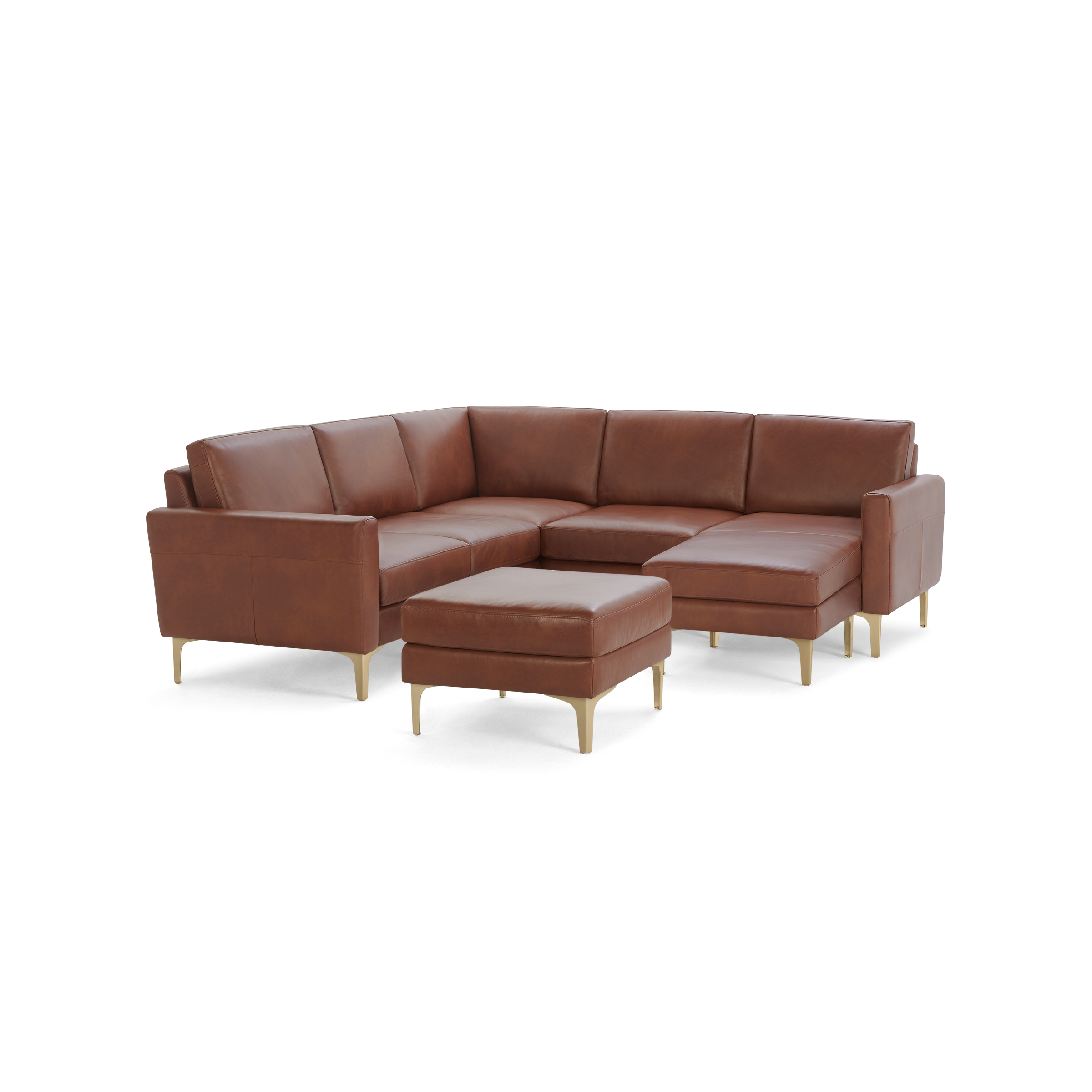Brown leather L-shaped sectional sofa with a matching ottoman and gold metal legs on a black background.