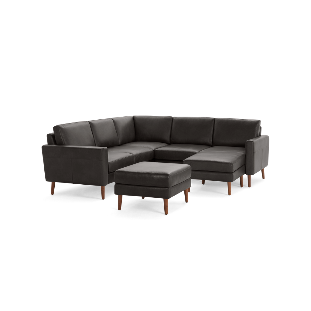Modern dark gray leather sectional sofa with wooden legs and matching ottoman, offering comfortable seating and stylish design.