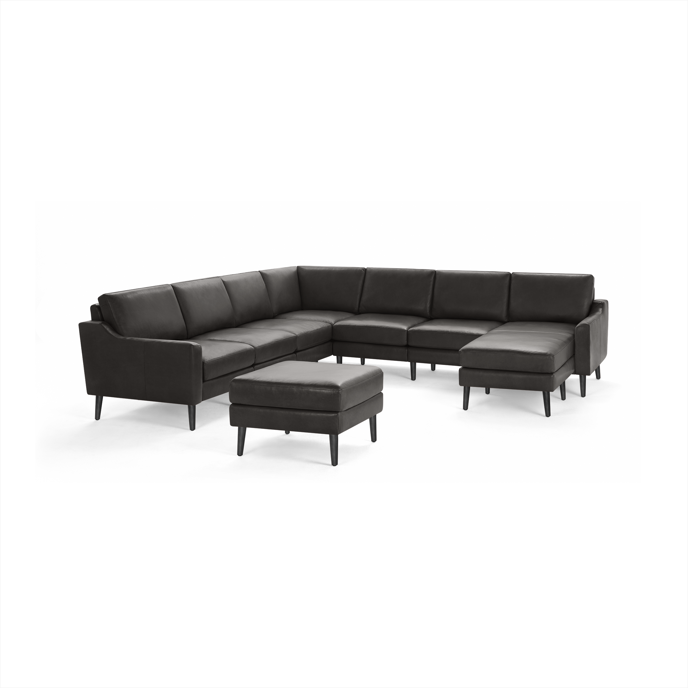 Dark gray leather upholstered L-shaped sectional sofa with matching ottoman, featuring soft cushions and tapered black wooden legs.