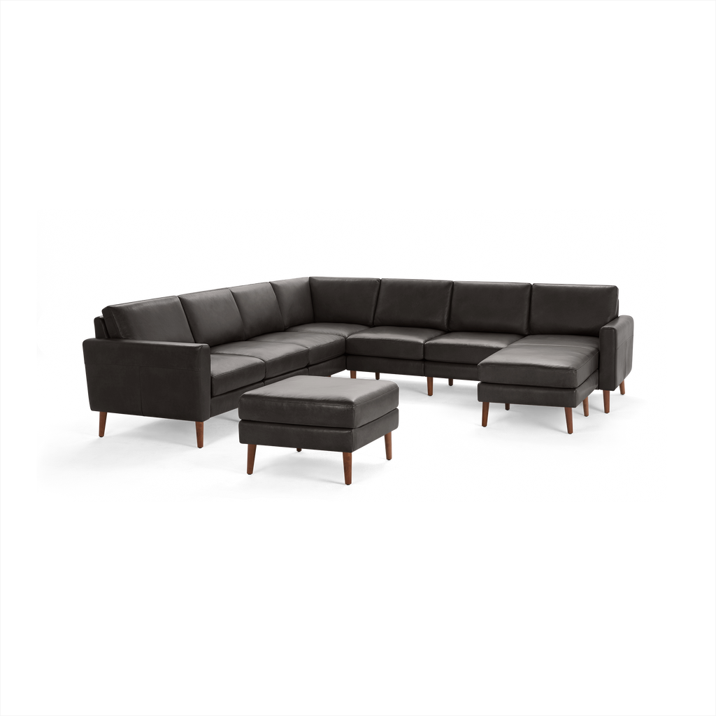 Modern dark gray L-shaped sectional sofa with matching ottoman, wooden tapered legs, and cushioned seating for multiple people.
