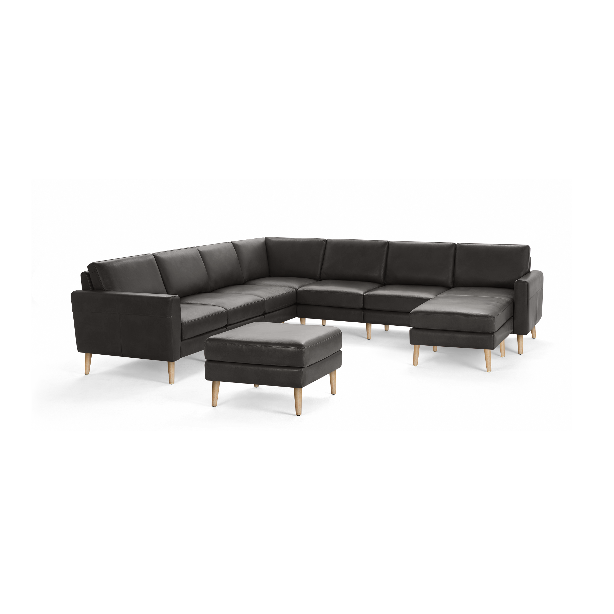 Dark gray leather sectional sofa with wooden legs and matching ottoman, modern design with cushioned seats and backs.