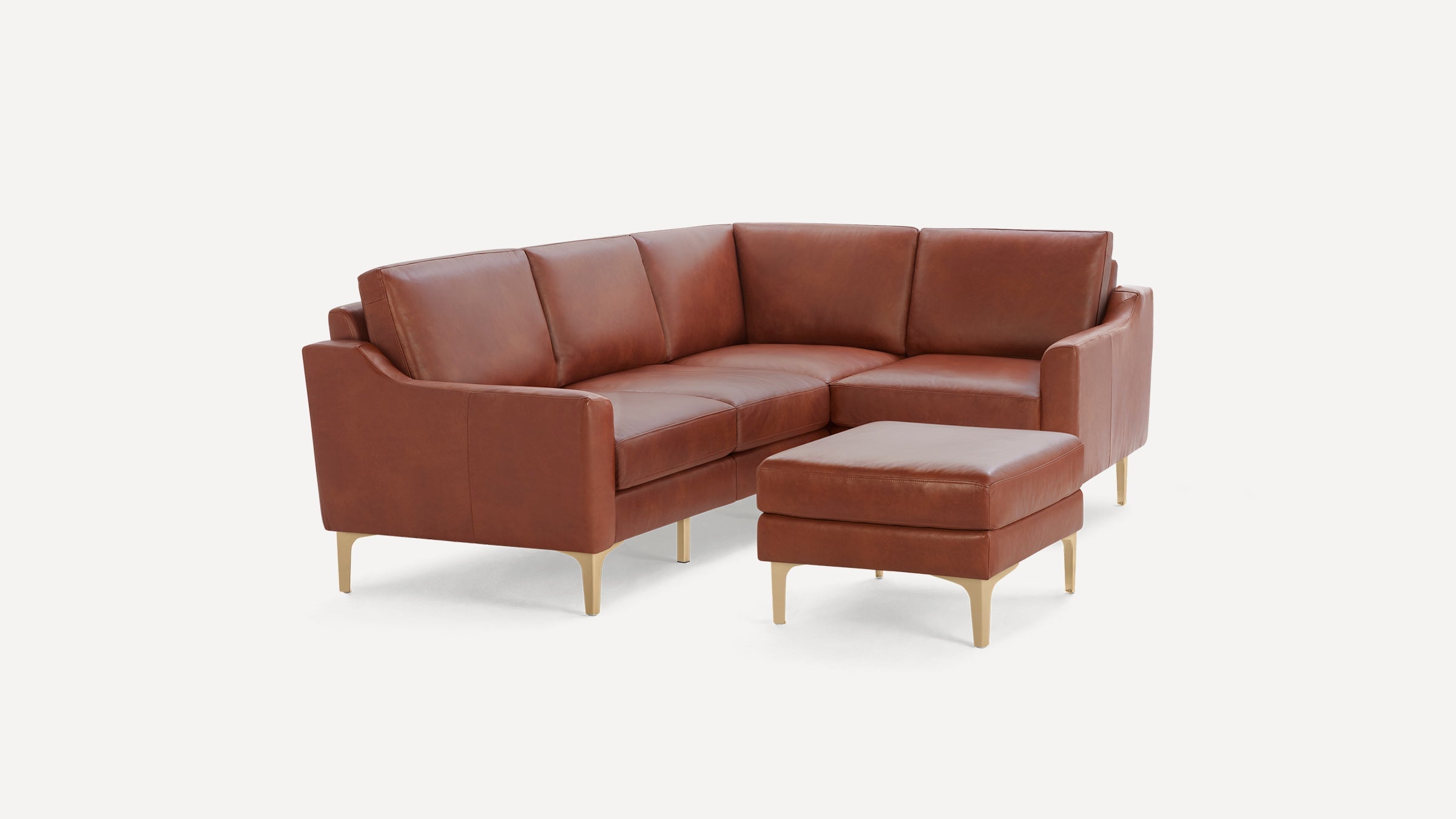 Brown leather sectional sofa with matching ottoman, supported by light wooden legs, shown on white background.