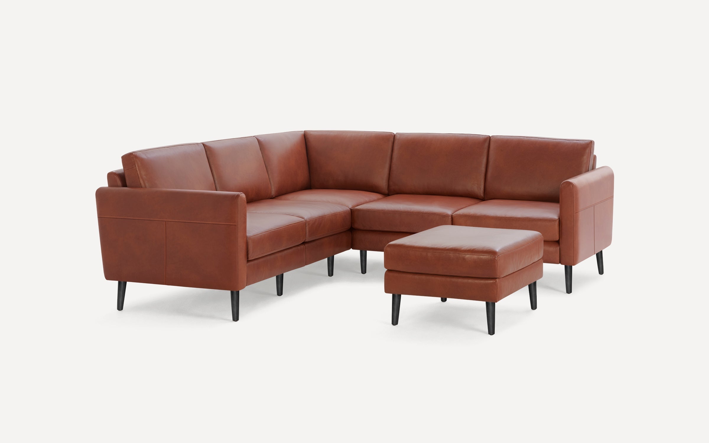Modern brown leather sectional sofa with black tapered legs, featuring an L-shape design and a matching ottoman.