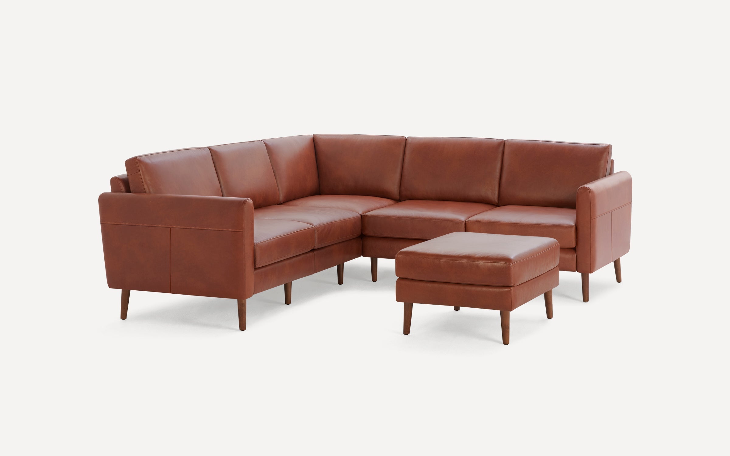 Mid-century modern brown leather sectional sofa with matching ottoman, clean lines, and wooden tapered legs on white background.