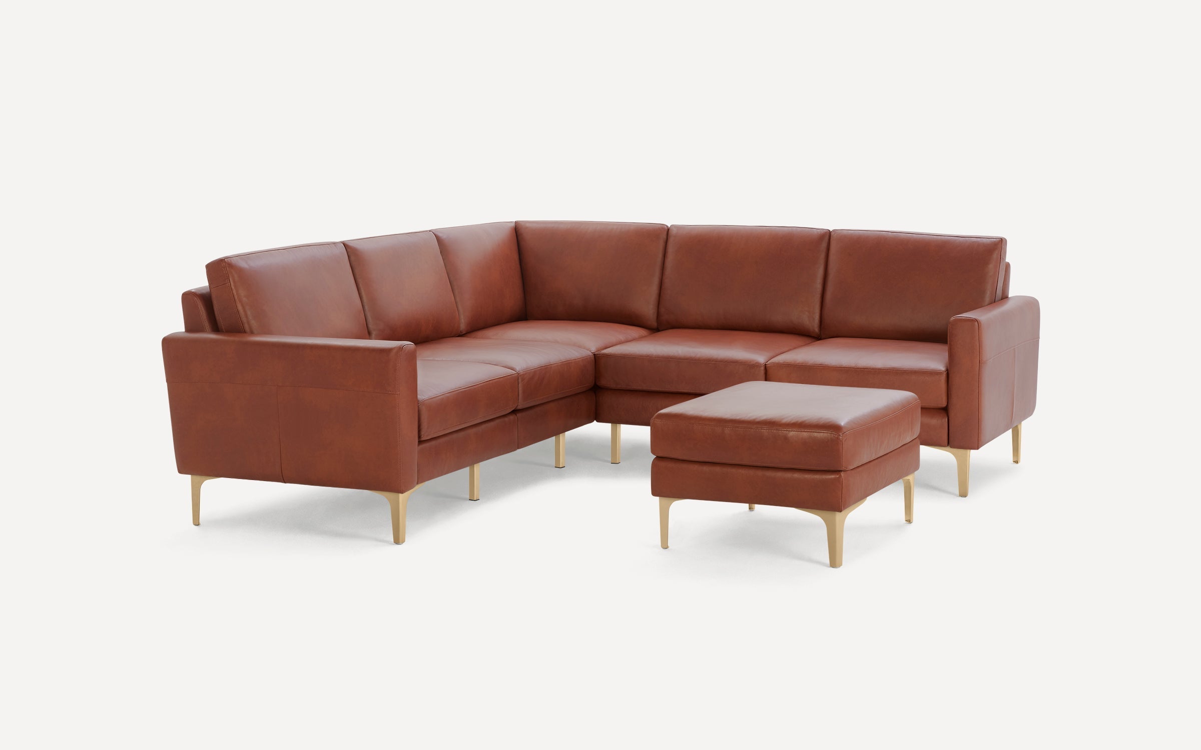 Brown leather L-shaped sectional sofa with matching ottoman, featuring slim gold legs and modern design.