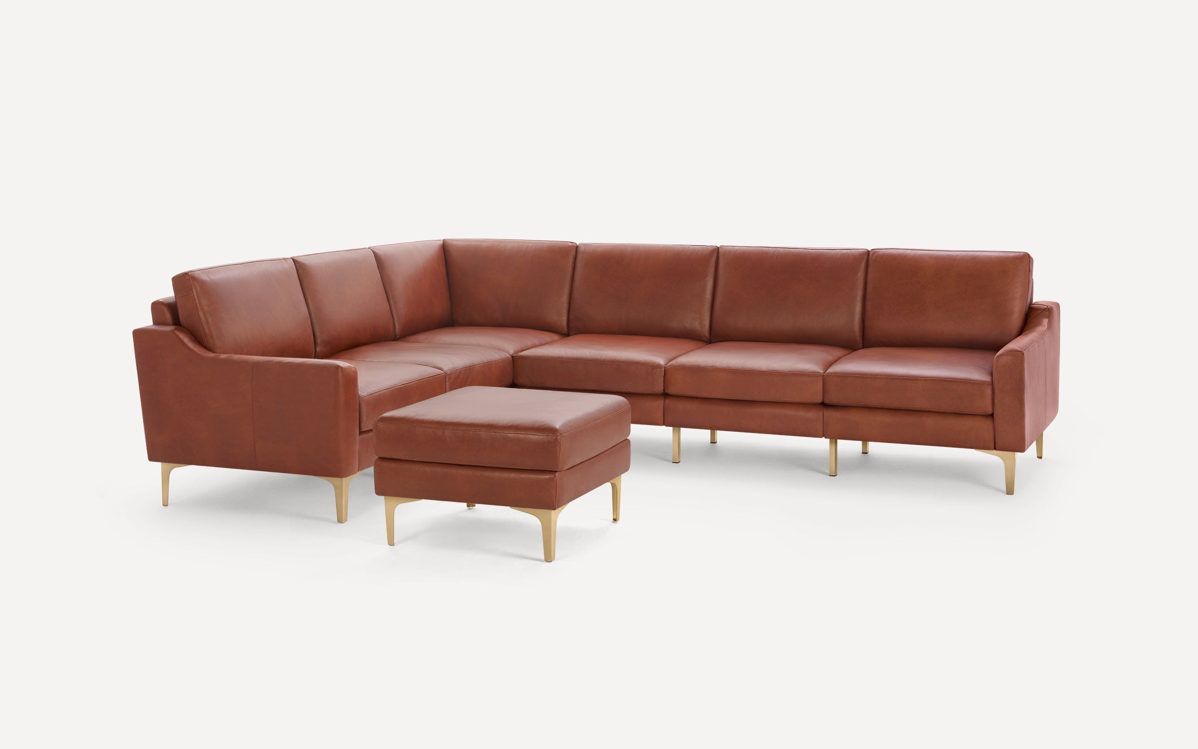 Modern brown leather sectional sofa with gold metal legs and matching ottoman, displayed on white background.