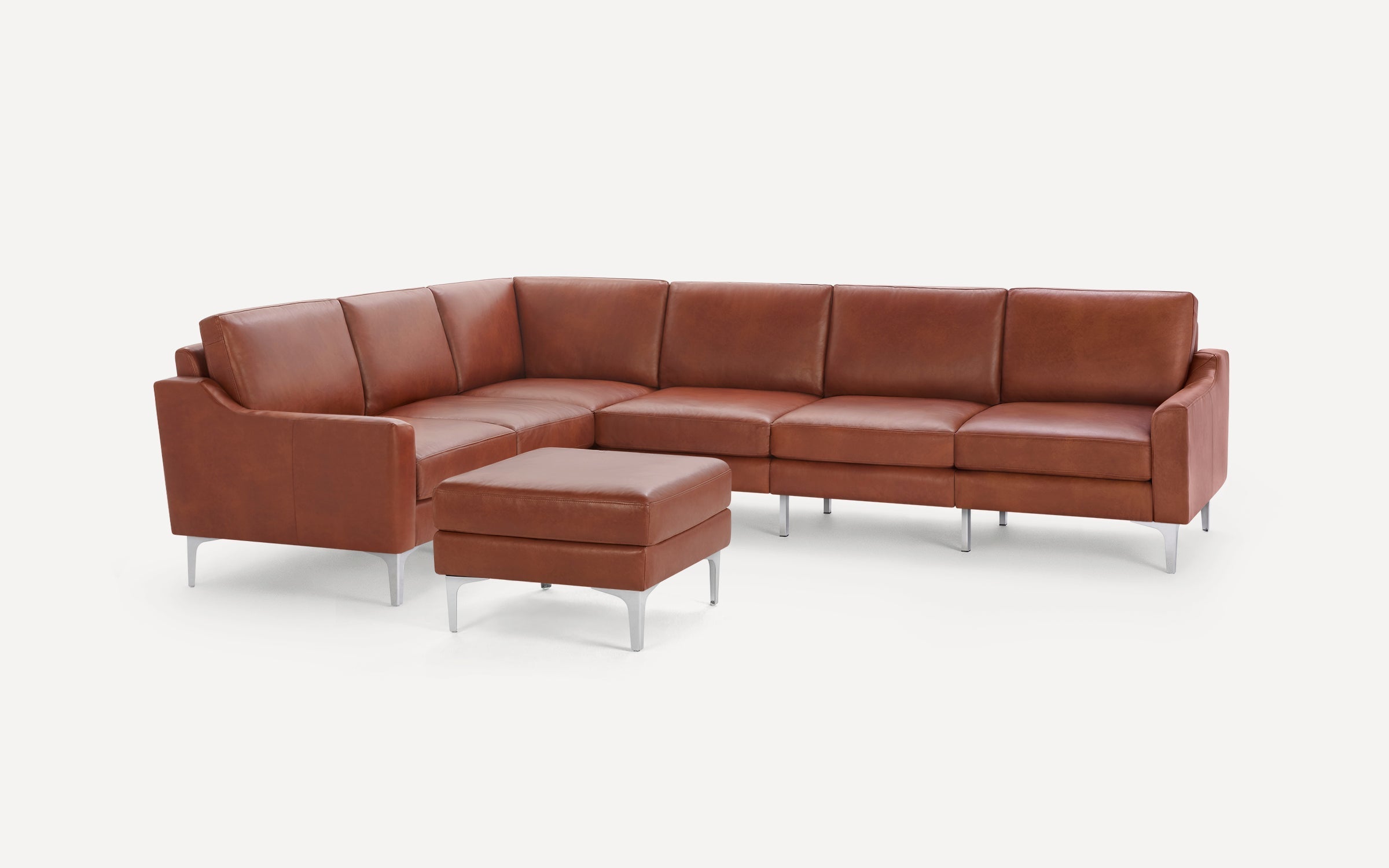 Modern brown leather sectional sofa with matching ottoman, featuring sleek metal legs and clean lines on white background.