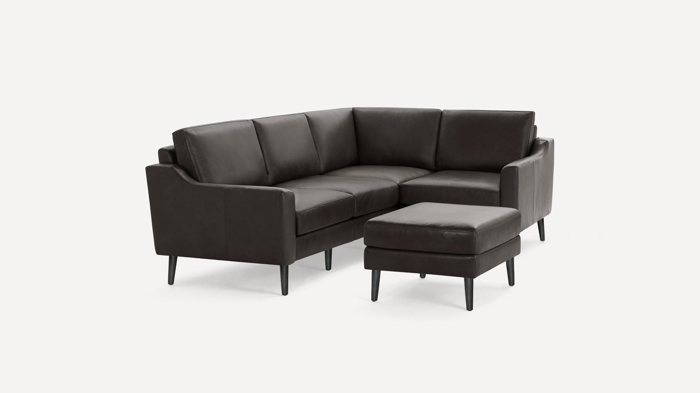 Dark brown leather sectional sofa with matching ottoman, featuring modern design and black tapered legs.
