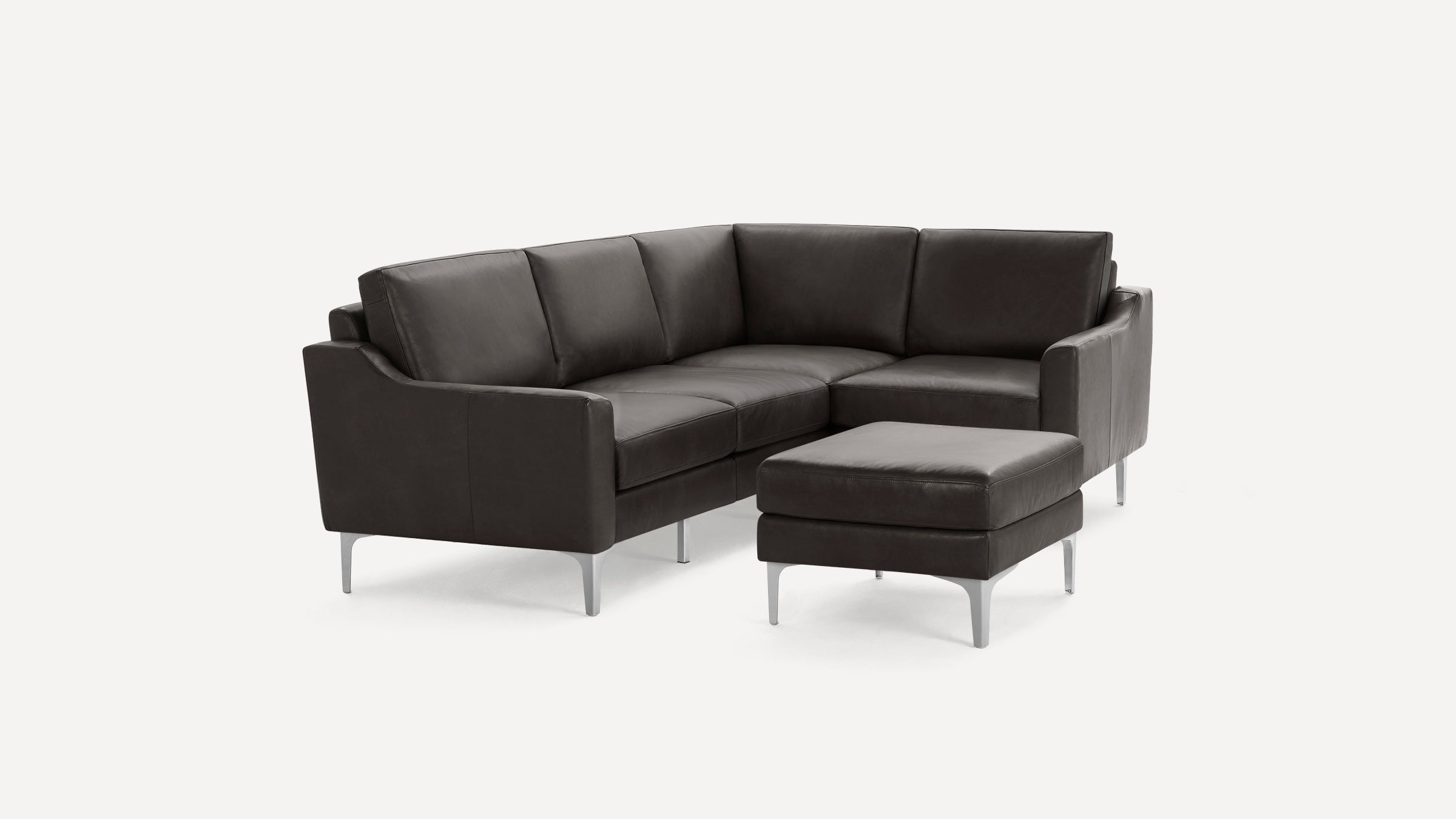 Modern dark gray leather L-shaped sectional sofa with matching ottoman and slim metal legs on white background.
