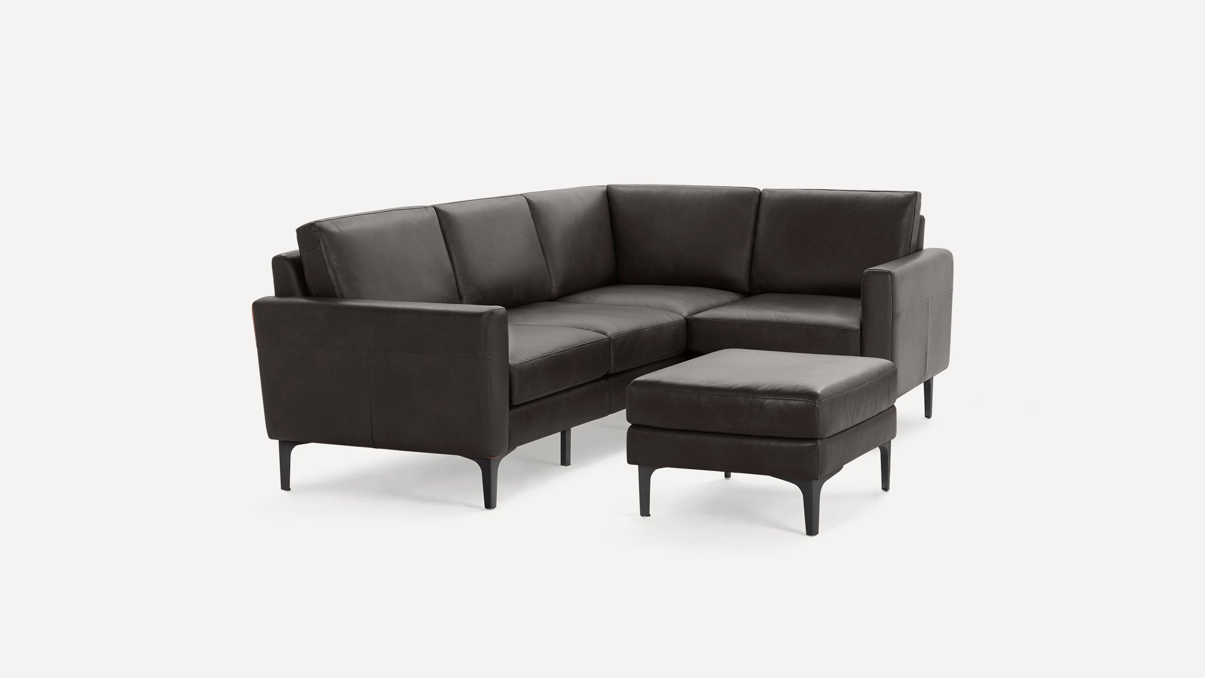 Modern dark gray leather sectional sofa with clean lines and matching cushioned ottoman on slender black legs.