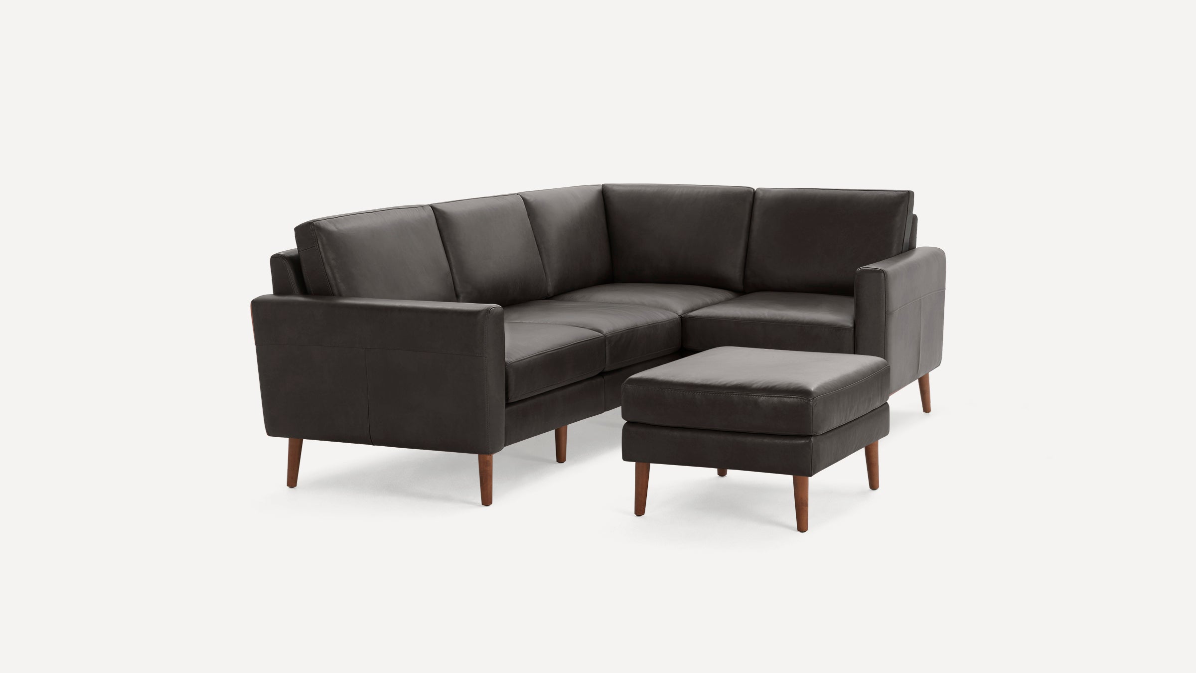 Dark gray leather mid-century modern sectional sofa with wooden legs and matching ottoman.