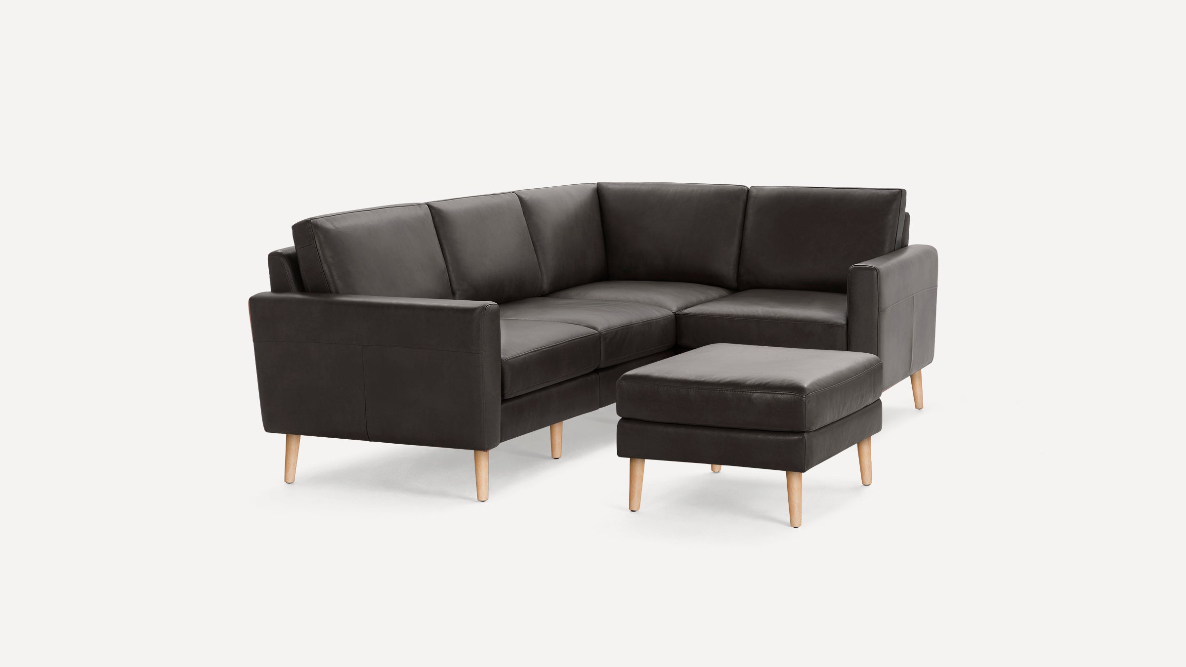 Dark brown leather L-shaped sectional sofa with clean lines and light wooden legs, accompanied by a matching ottoman.