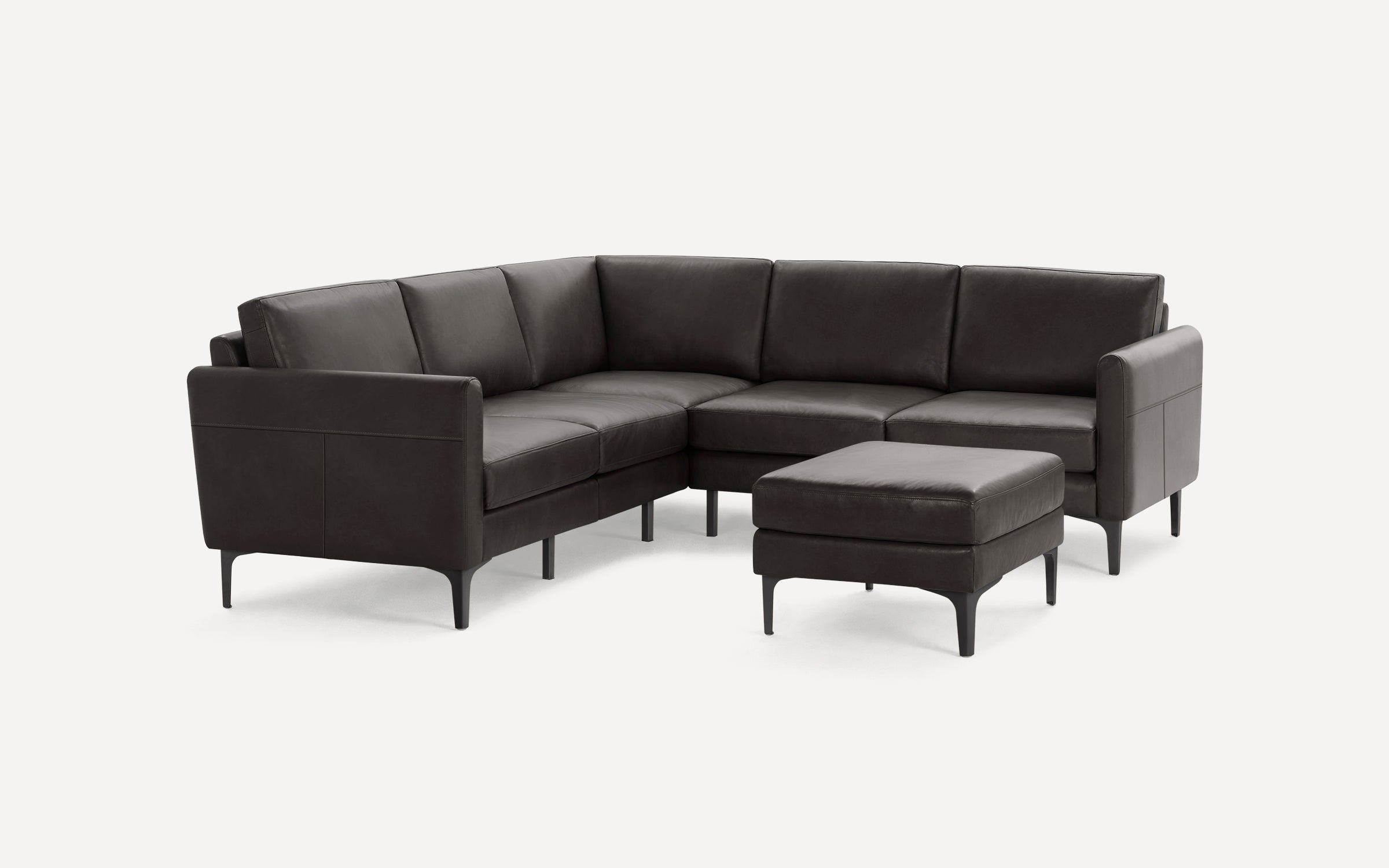 Modern dark brown leather L-shaped sectional sofa with slim black legs and matching ottoman on white background.