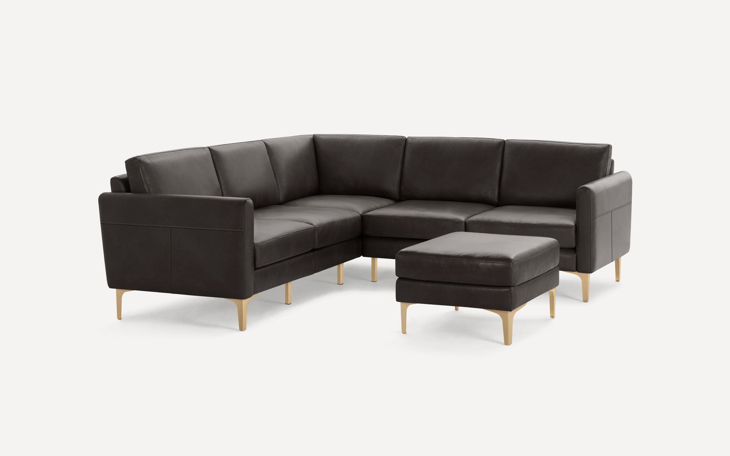 Modern dark brown leather L-shaped sectional sofa with matching ottoman and light wood legs on white background.