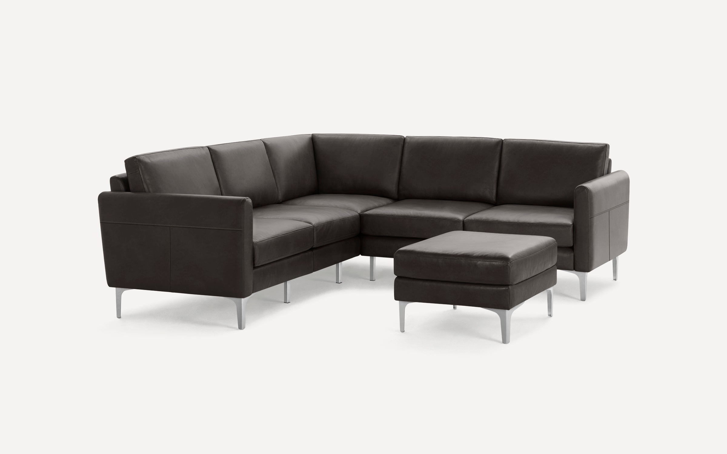 Modern dark gray leather sectional sofa with metal legs and matching ottoman on a white background.
