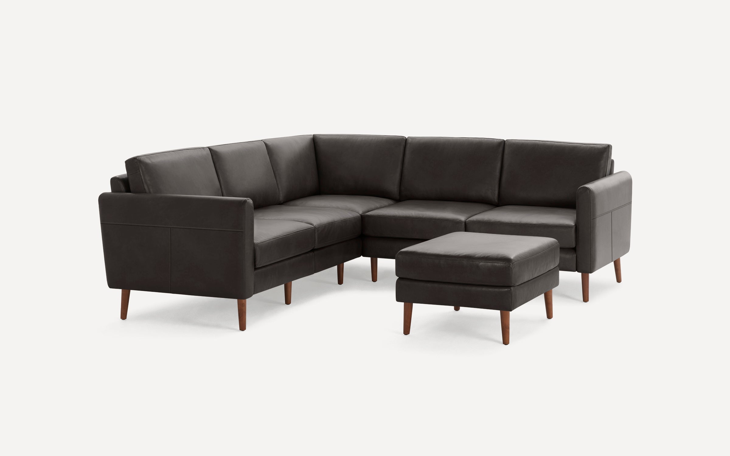Dark brown leather L-shaped sectional sofa with matching ottoman, featuring wooden legs and clean, modern design.