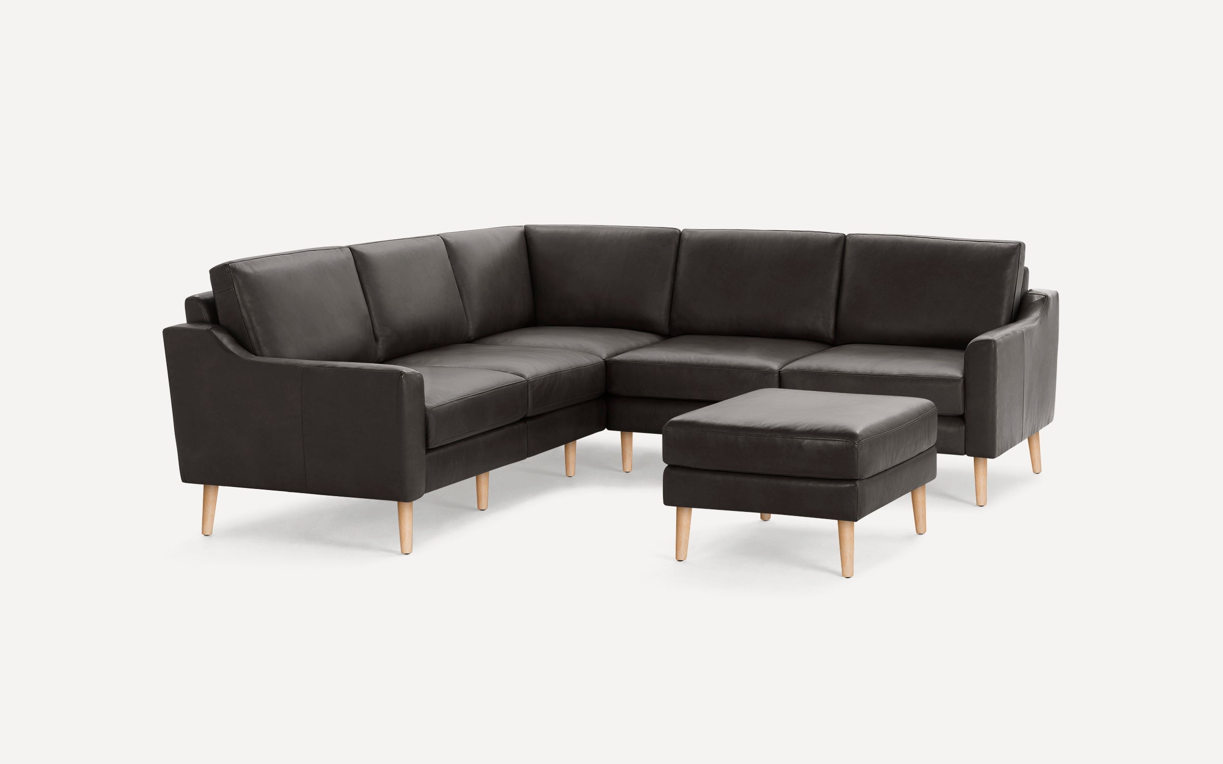 Dark gray L-shaped sectional sofa with matching ottoman, featuring wooden legs and cushioned seats and backs.