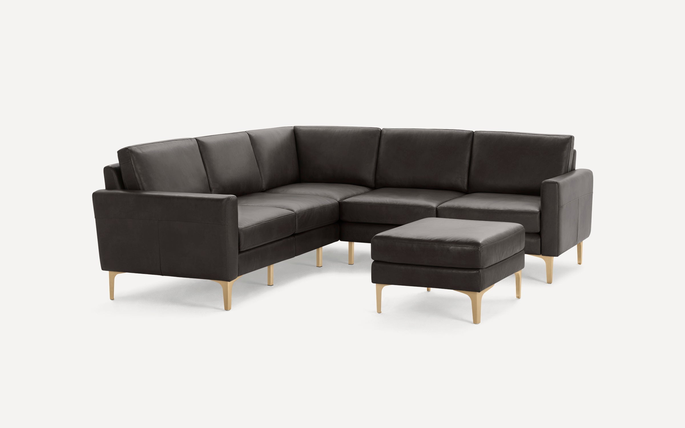 Modern dark brown leather L-shaped sectional sofa with plush cushions and matching ottoman, supported by light wooden legs.