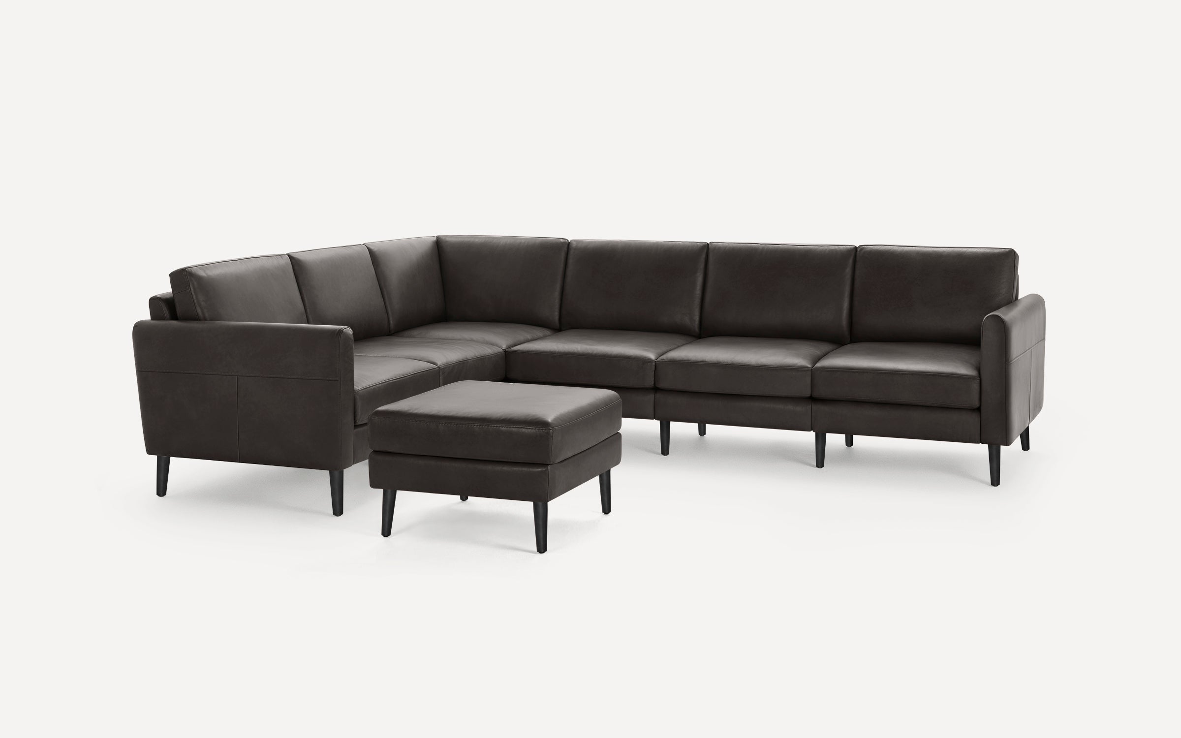 Dark gray leather sectional sofa with chaise and matching ottoman, featuring clean lines and black tapered legs.