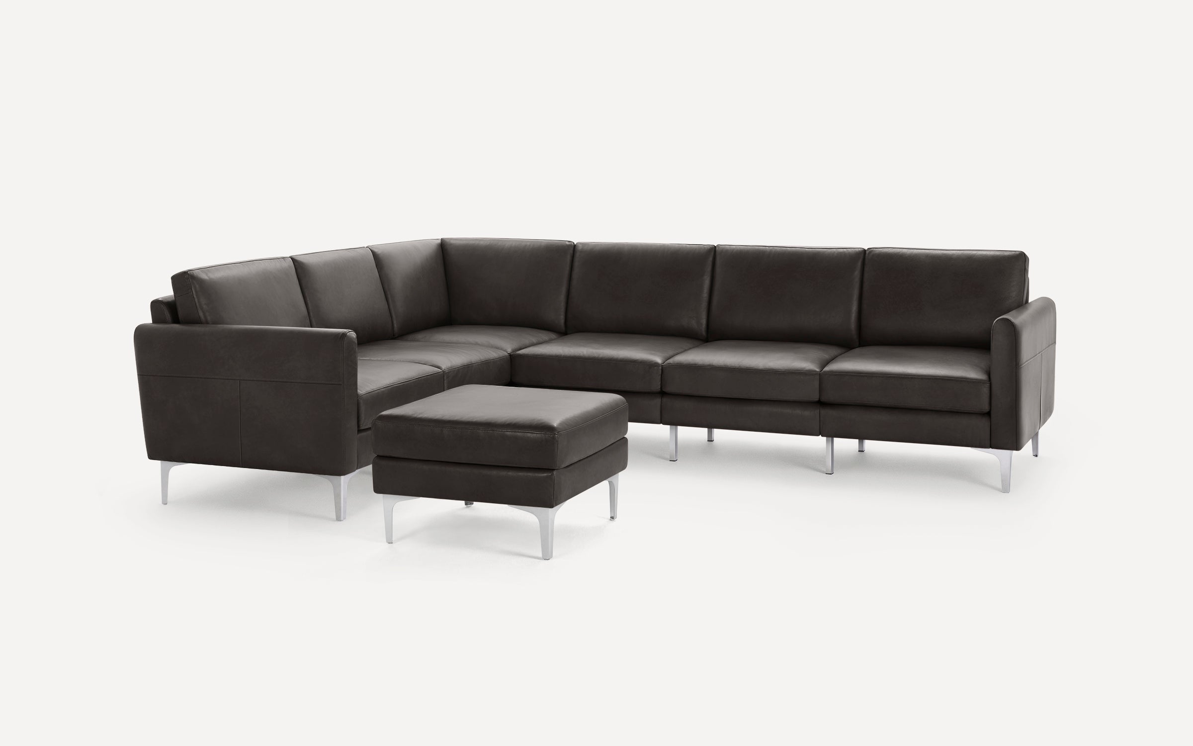Dark gray leather sectional sofa with clean lines, silver metal legs, and matching padded ottoman on white background.