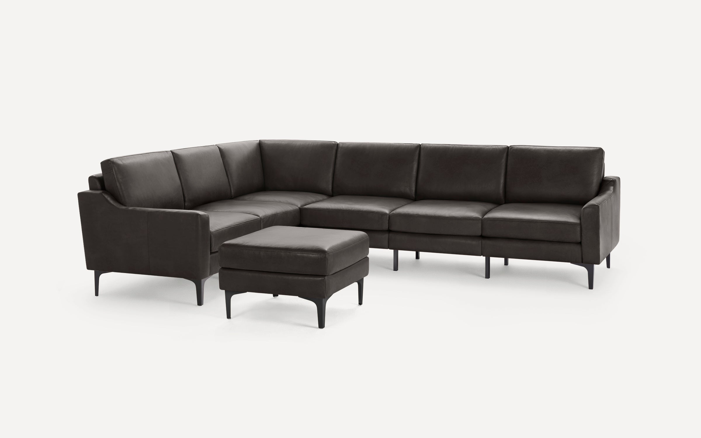 Dark brown L-shaped sectional sofa with matching ottoman, sleek design, thin black legs, and smooth leather upholstery.