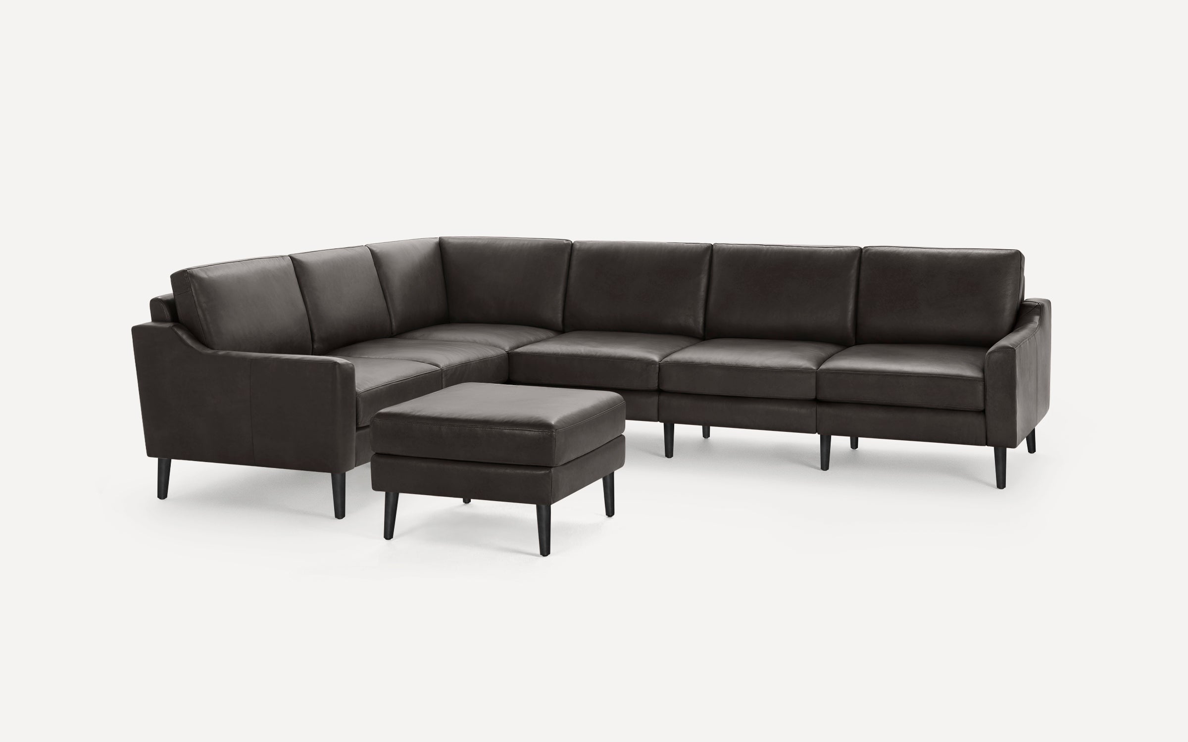 Dark brown leather L-shaped sectional sofa with matching ottoman, tapered black legs, and clean modern design.