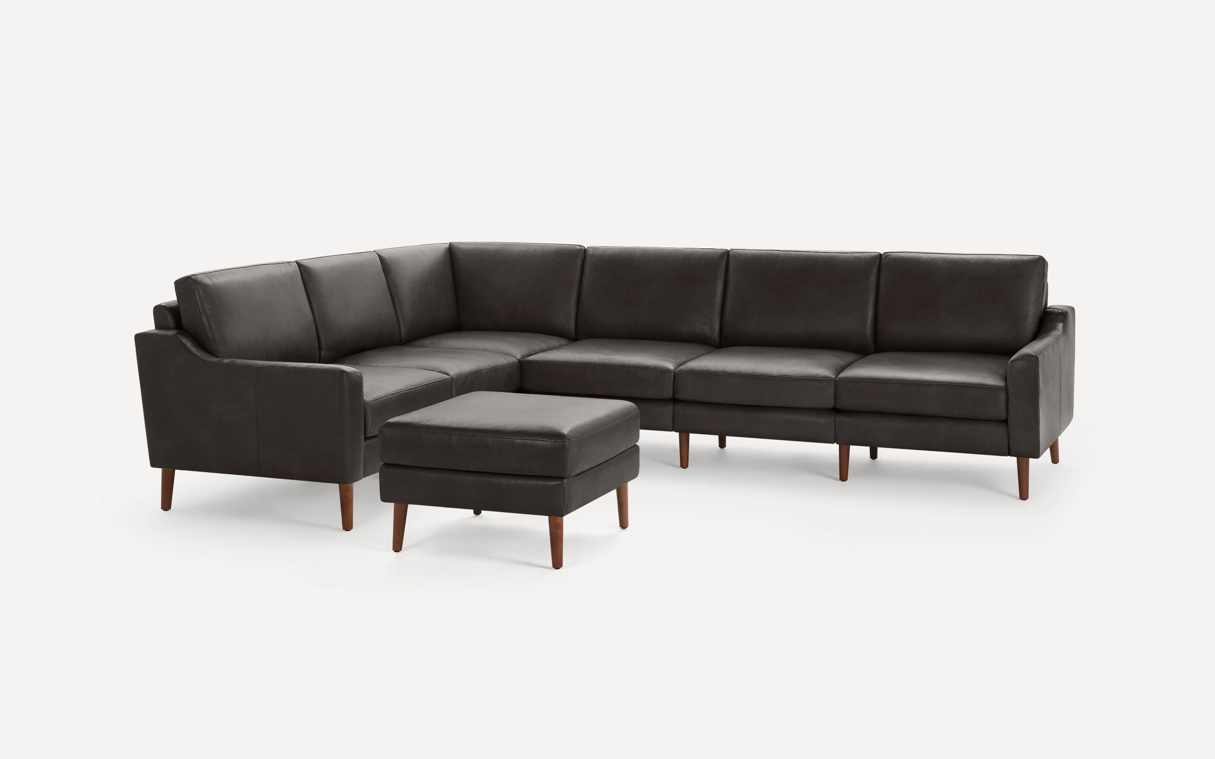 Dark brown leather sectional sofa with clean lines, wooden tapered legs, and a matching square ottoman on a white background.