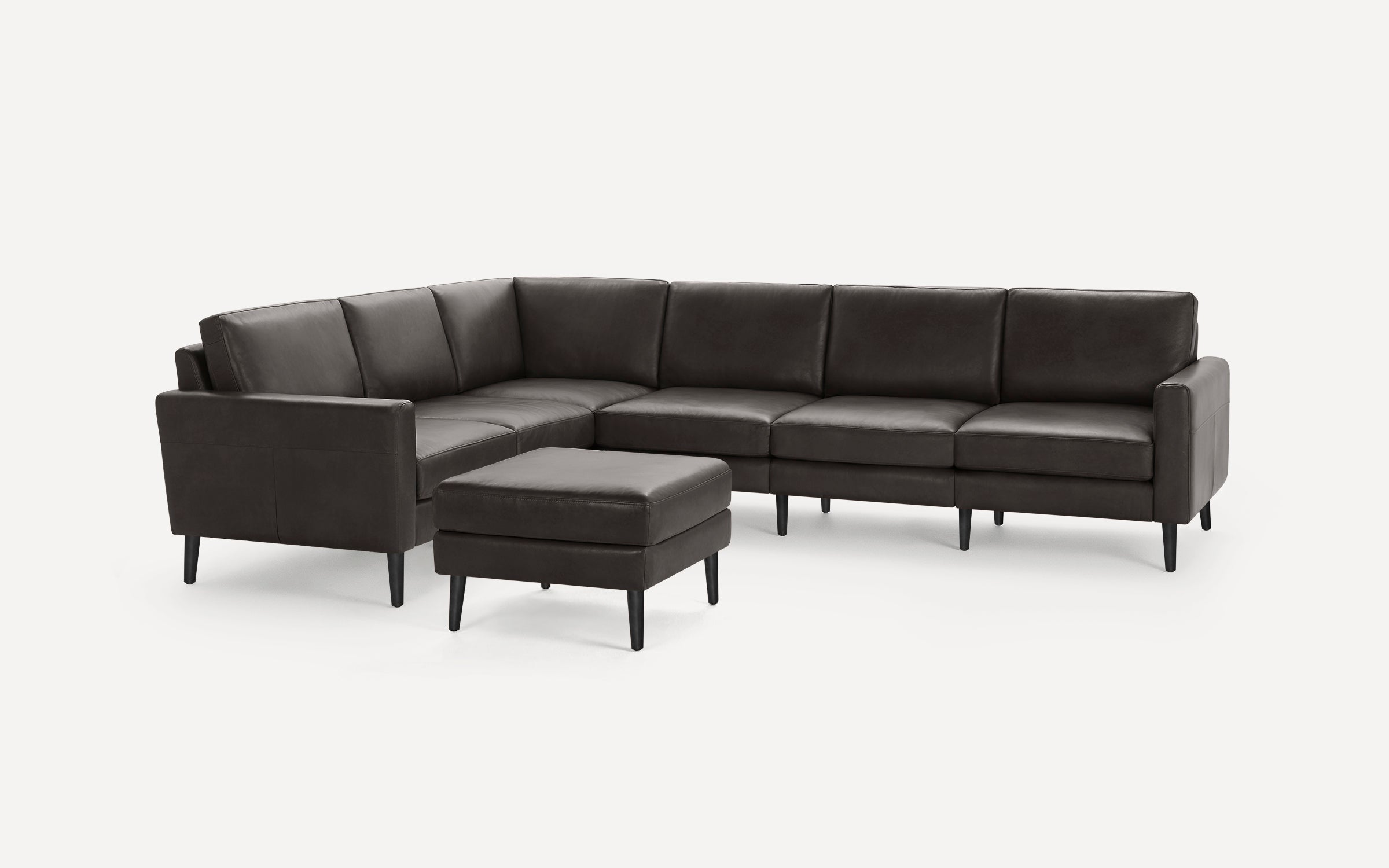 Dark brown leather sectional sofa with clean lines and slim black legs, accompanied by a matching ottoman.