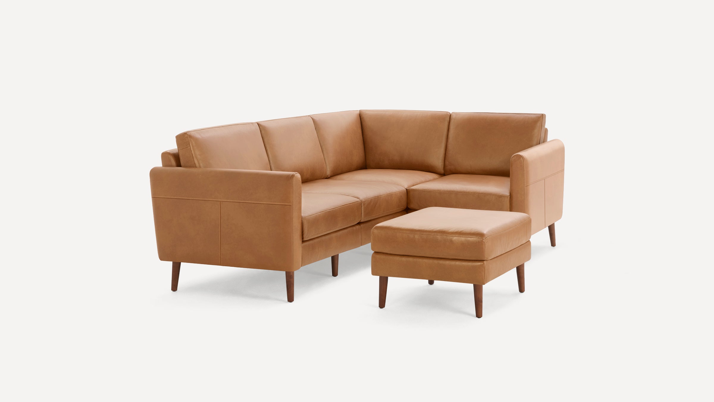 Modern tan leather L-shaped sectional sofa with matching ottoman, featuring clean lines and wooden tapered legs.