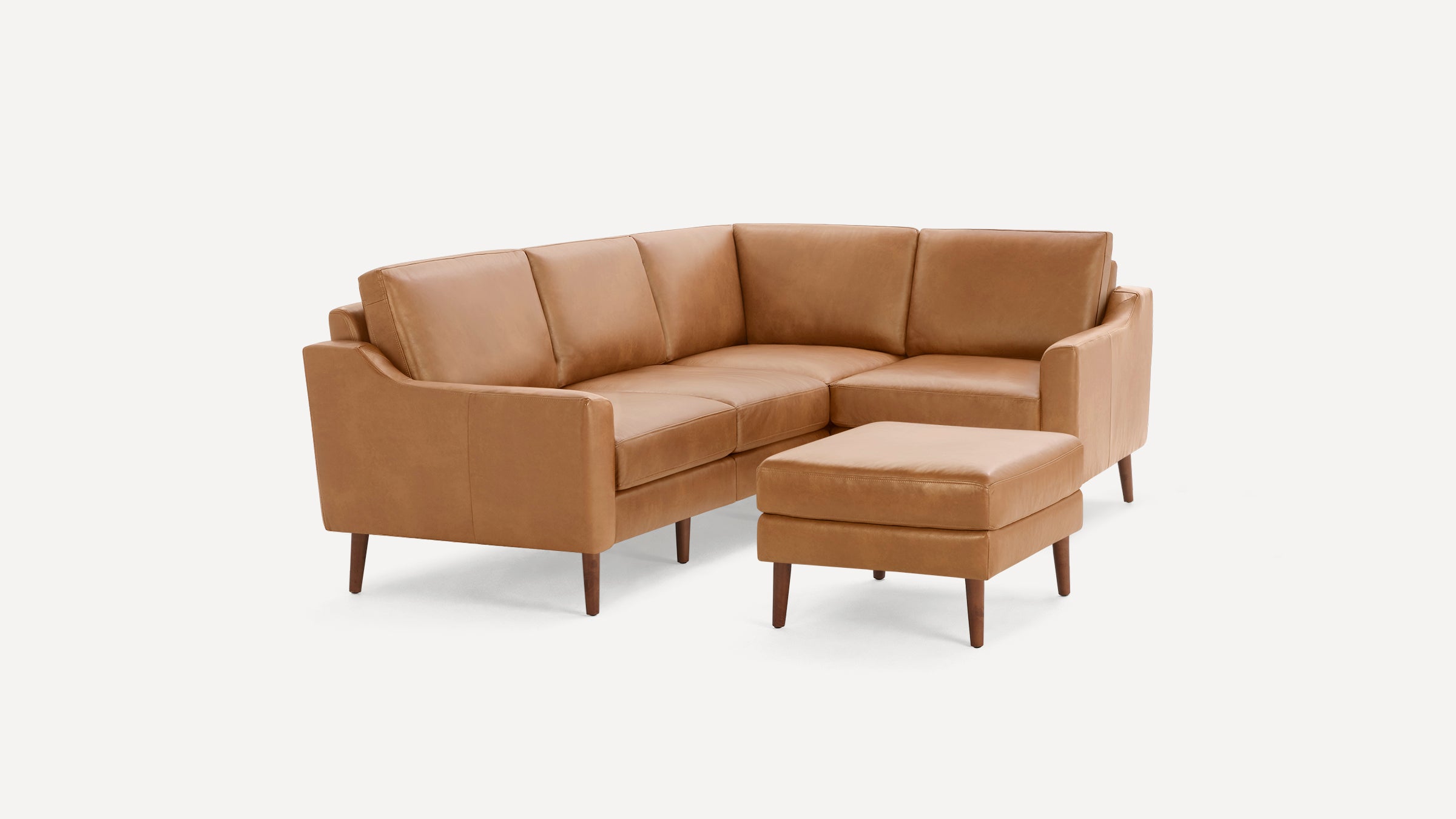 Modern mid-century style brown leather sectional sofa with wooden legs and matching ottoman on white background.