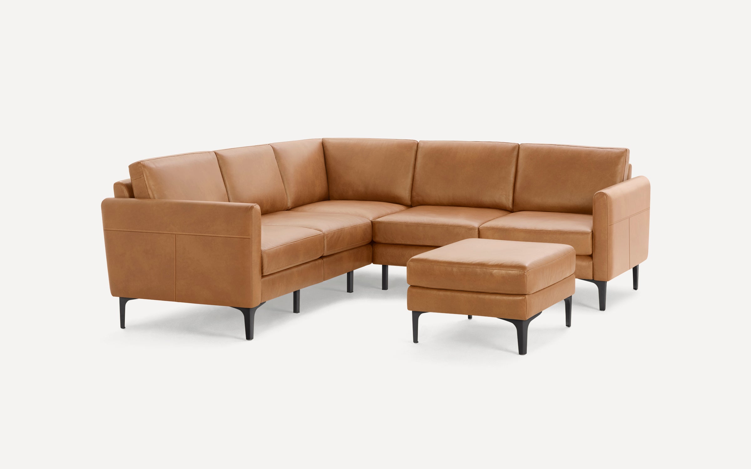 Modern tan leather sectional sofa with matching ottoman, featuring slim black legs and padded armrests.