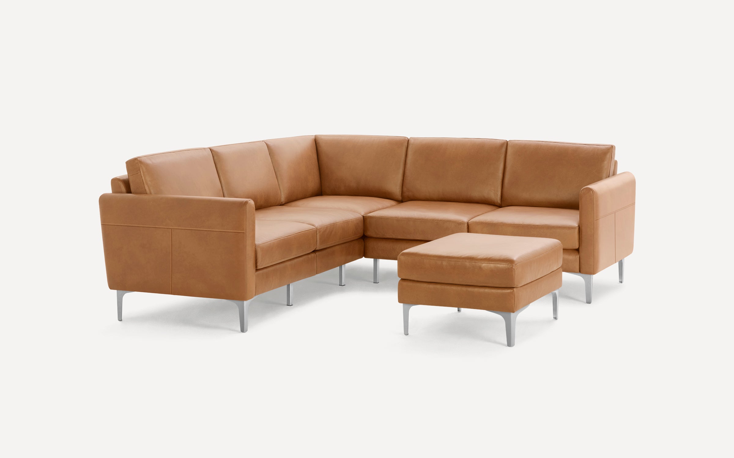 Modern L-shaped tan leather sectional sofa with clean lines and metal legs, accompanied by a matching ottoman.
