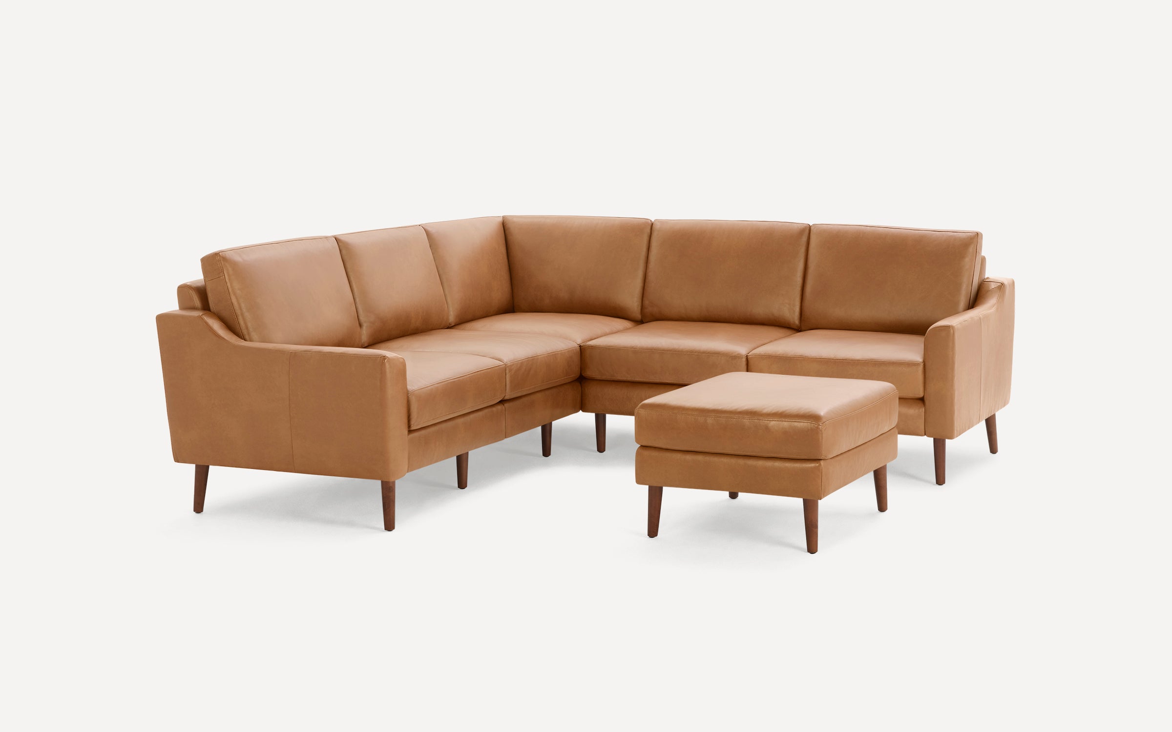 Modern tan leather sectional sofa with clean lines and wooden legs, accompanied by a matching ottoman.